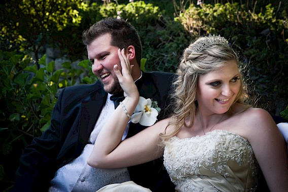 Talk to the hand! A bride playfully pushes her husband away, jokingly pretending to dismiss him, while both share a laugh – Photo by Greg Lumley.