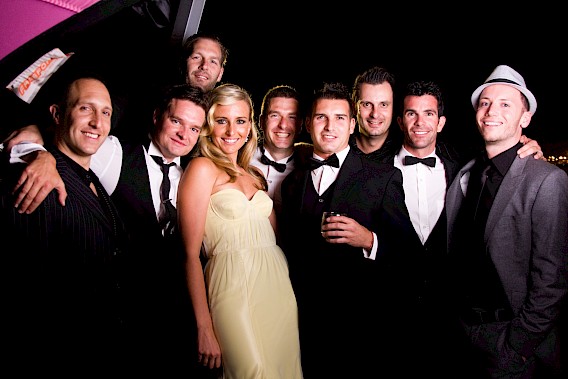 Playful photo of an elegant blonde birthday girl in a stylish dress posing with a group of boys.