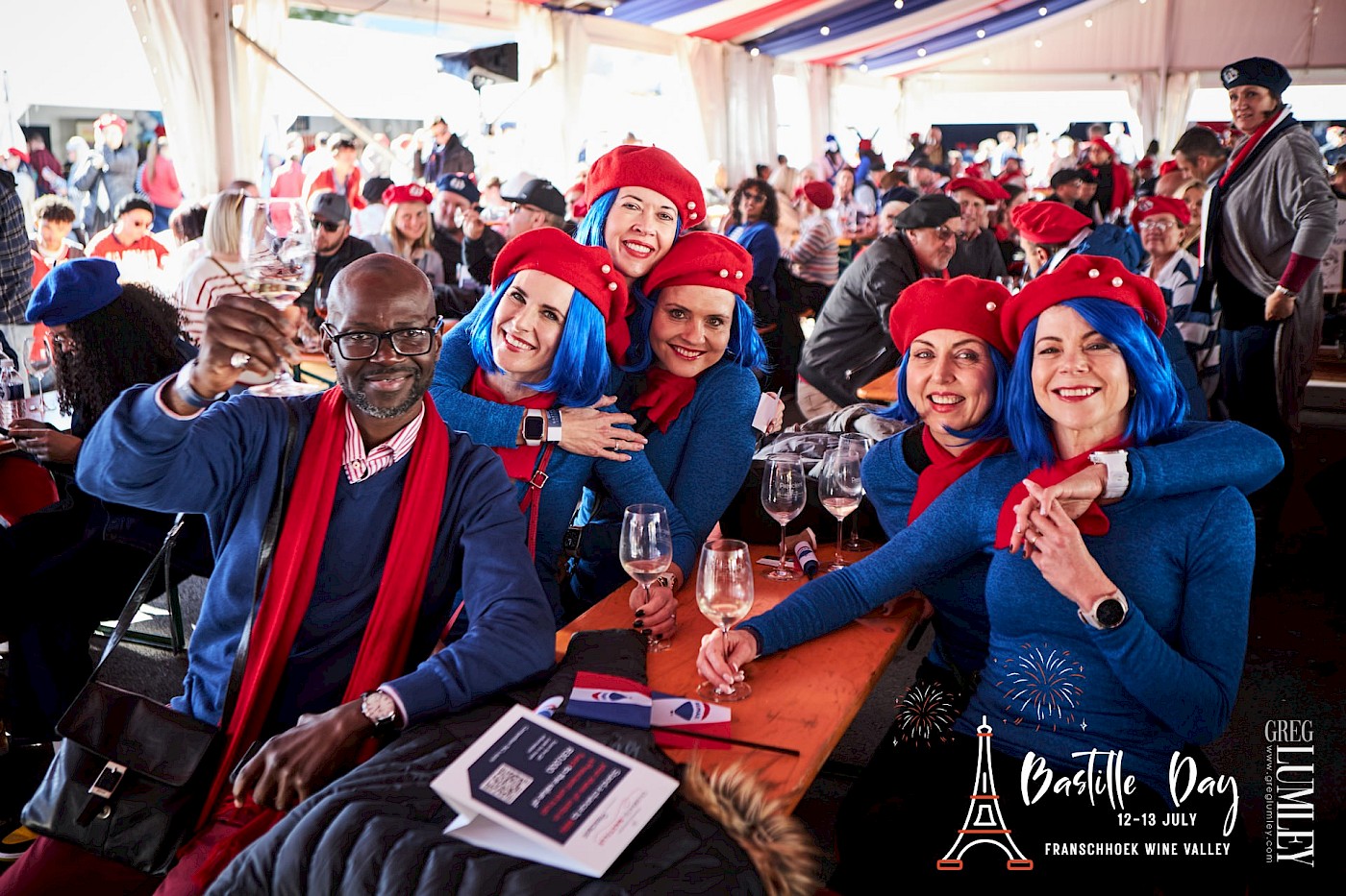 Five women dressed in red berets, red scarves, and blue jerseys celebrating Bastille Day in Franschhoek