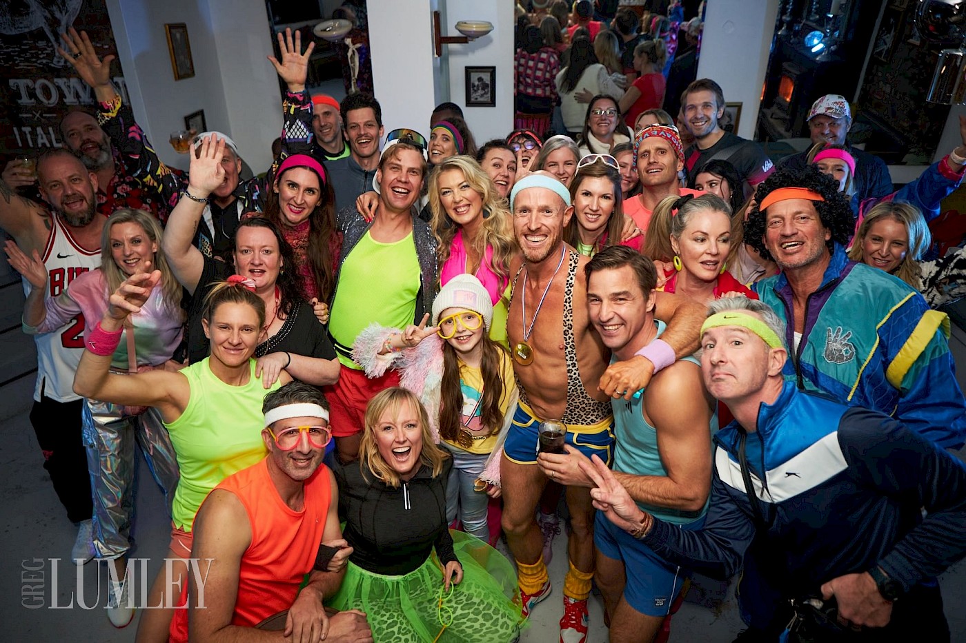 Fun group photo of approximately 30 people wearing bright active wear for a 40th birthday party theme